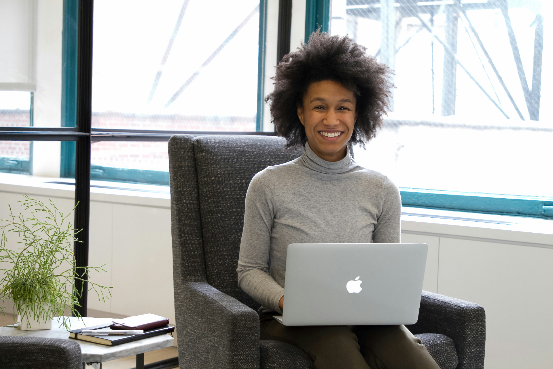 A founder smiling while working on her laptop in a sunlit space